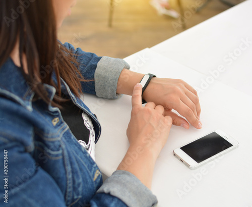 Close-up portrait of a girl using a fitness tracker or heart rate monitor. View the number of steps per day. Fitness concept. A woman looks at the results of training on a fitness bracelet. 