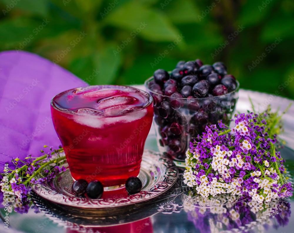 Composition from berries of Aronia in a glass on a metal tray. Berries of Aronia in a glass cup. Compote with ice Composition from berries of Aronia in a glass on a metal tray. Berries of Aronia in a glass cup. Compote with ice