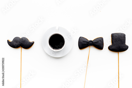 Father's Day celebration concept. Monochrome. Cookies in shape of moustache, hat, bow tie near coffee on white background top view copy space