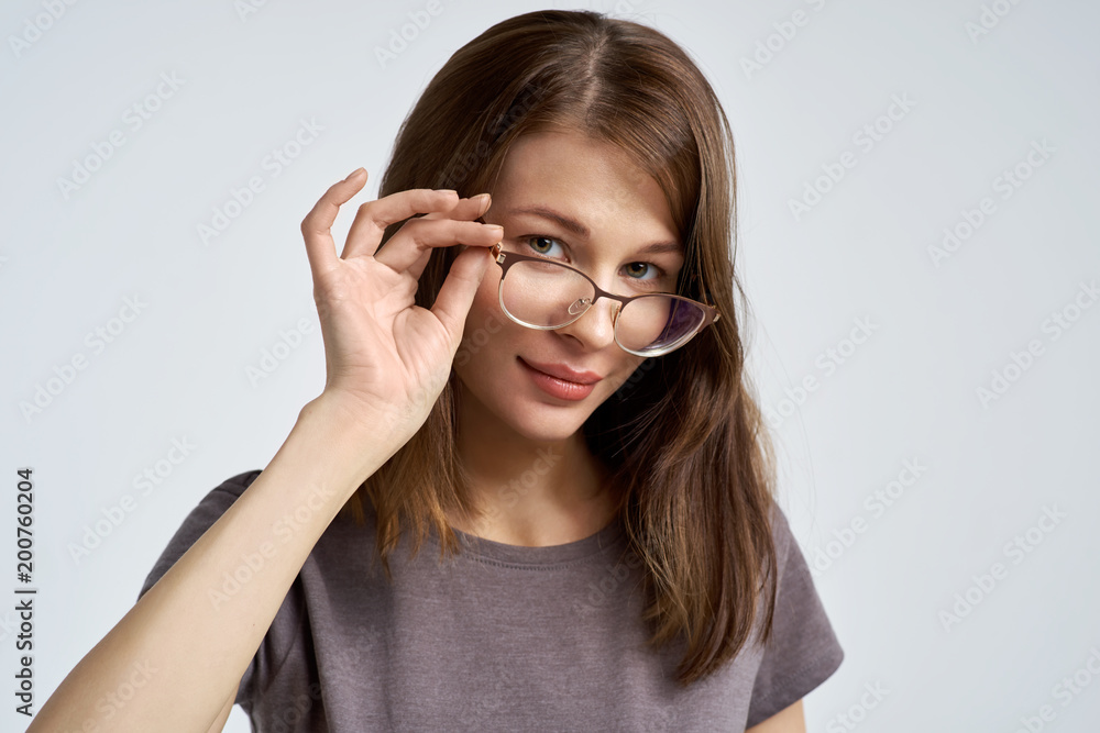 attractive young brunette woman corrects her glasses and looks attentively at the camera. Large horizontal portrait attractive young brunette woman corrects her glasses and looks attentively at the camera. Large horizontal portrait