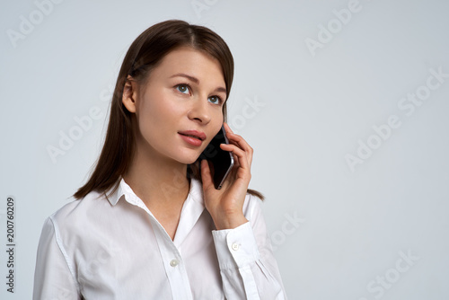 beautiful young business lady woman in white shirt with serious expression talking on the phone. Close-up