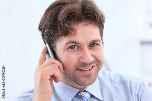 handsome businessman sitting at Desk and talking on a cell phone