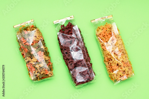 Dried pasta in bag front view. Colorful vegetable pastas on yellow isolated background