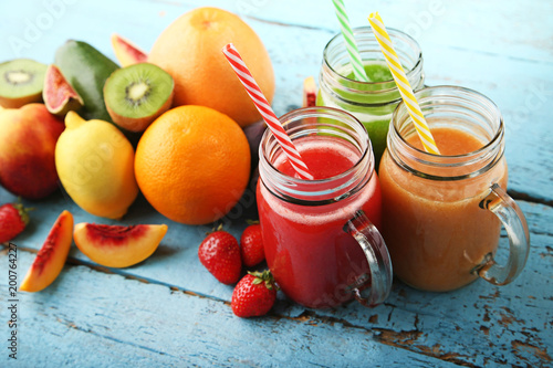 Sweet smoothie in glass jars with fruits on blue wooden table