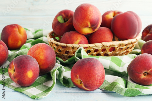 Sweet nectarines in basket on white wooden table