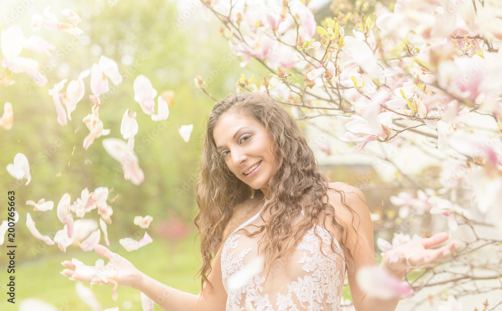 Fototapeta premium hübsches mädchen im frühling vor blühenden magnolien bei sonnenschein