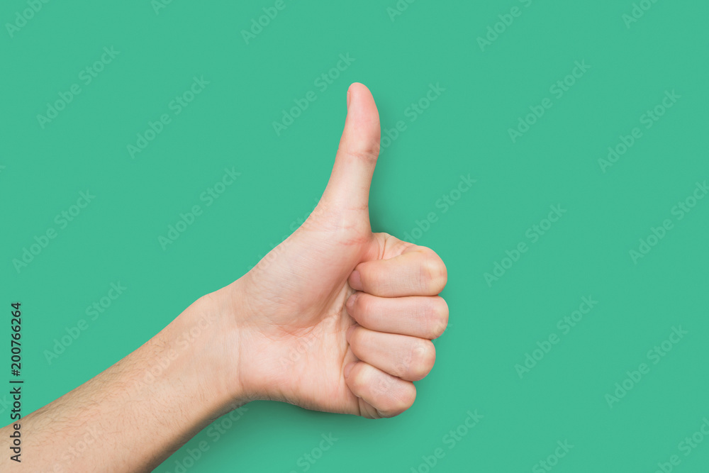 Male hand making thumb up gesture isolated on green