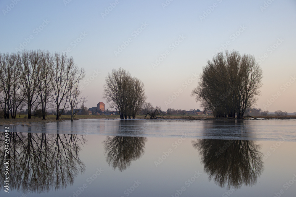 River in winter with church tower and small village in the background River in winter with church tower and small village in the background
