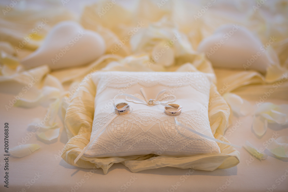 Wedding rings together with white rope on white pillow surrounded white hearts. Marriage ceremony Wedding rings together with white rope on white pillow surrounded white hearts. Marriage ceremony