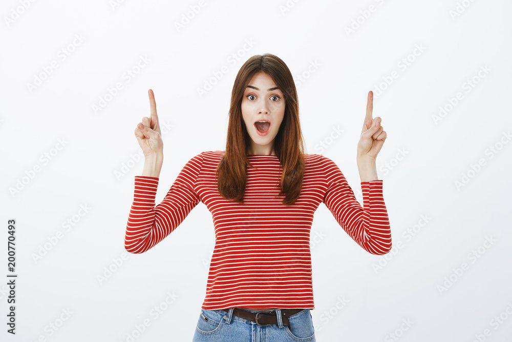 Special price waiting for us. Indoor shot of excited interested young european woman in red striped pullover, dropping jaw from amazement and pointing up, promoting or posing for advertisement Special price waiting for us. Indoor shot of excited interested young european woman in red striped pullover, dropping jaw from amazement and pointing up, promoting or posing for advertisement