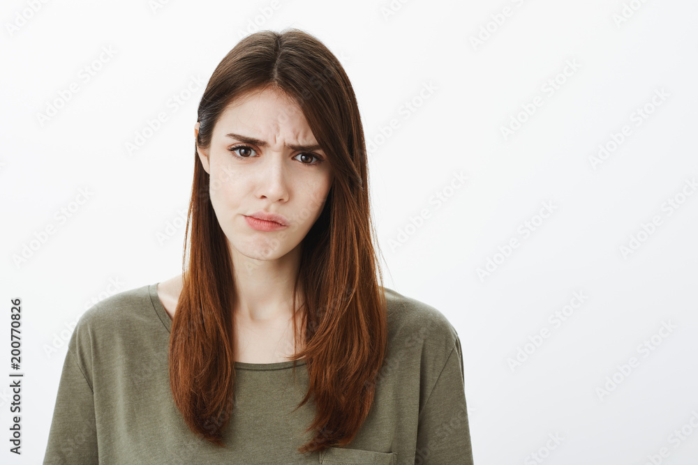 Attractive smart female coworker in casual clothes, frowning and expressing displeasure and disagreement, hearing nonsense or strange things, disliking conversation over gray background Attractive smart female coworker in casual clothes, frowning and expressing displeasure and disagreement, hearing nonsense or strange things, disliking conversation over gray background