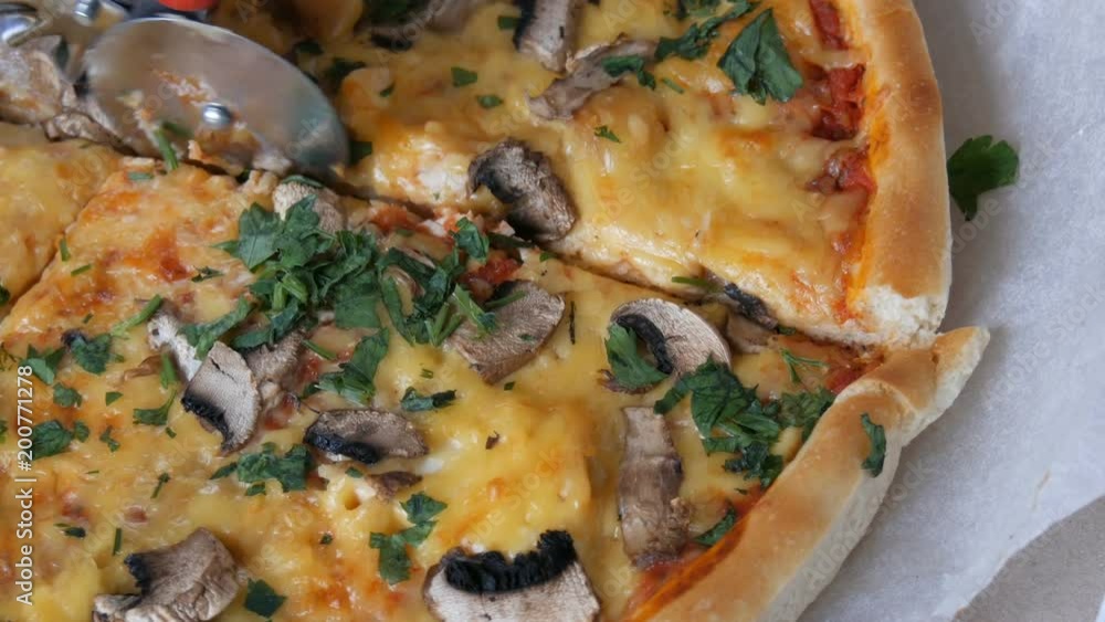 Woman's hand takes piece of round pizza withwith greens, chicken, mushrooms and double cheese Woman's hand takes piece of round pizza withwith greens, chicken, mushrooms and double cheese