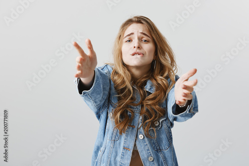 Desire blinded everything. Portrait of longing impratient attractive woman with blonde hair, wearing denim jacket, biting lip, pulling hands towards camera, being passionate, wanting something badly