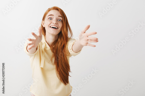 Come to me, let me hug you. Studio shot of thrilled overwhelmed redhead female pulling hands towards camera with affection in eyes, feeling desire to cuddle and express passionate emotions