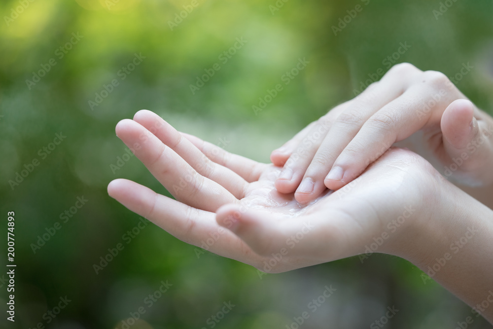 Closeup of female hands applying cream on her arm. Make up, healthy skin, beauty shot, cute asian woman concept Closeup of female hands applying cream on her arm. Make up, healthy skin, beauty shot, cute asian woman concept