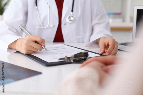 Fototapeta Naklejka Na Ścianę i Meble -  Close up of a female doctor filling up  an application form while consulting patient