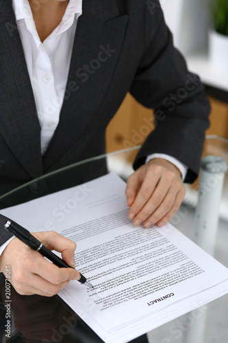 Close-up of female hands with pen over document, business concept