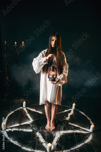 Woman holds kerosene lamp, pentagram circle, magic