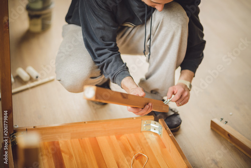 man screws the legs to a wooden table