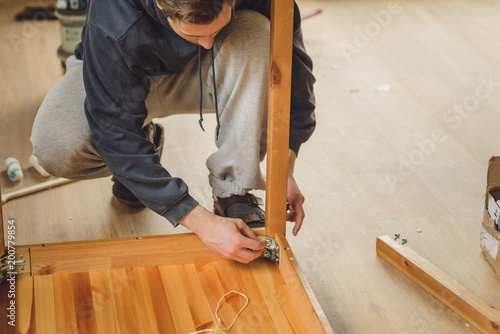 man screws the legs to a wooden table