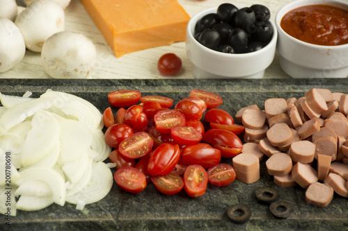 Ingredients for Italian pizza with cheddar cheese, mushrooms, black olives and sausage on white wooden background 