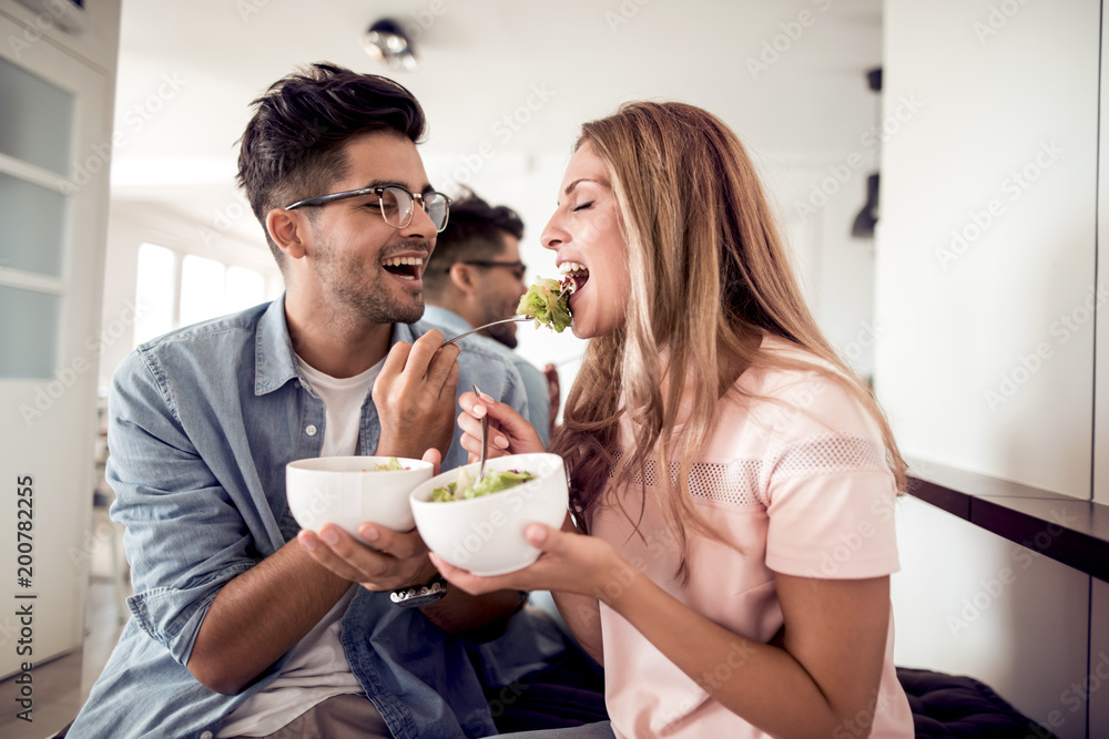 Young couple eating salad in a living room Young couple eating salad in a living room