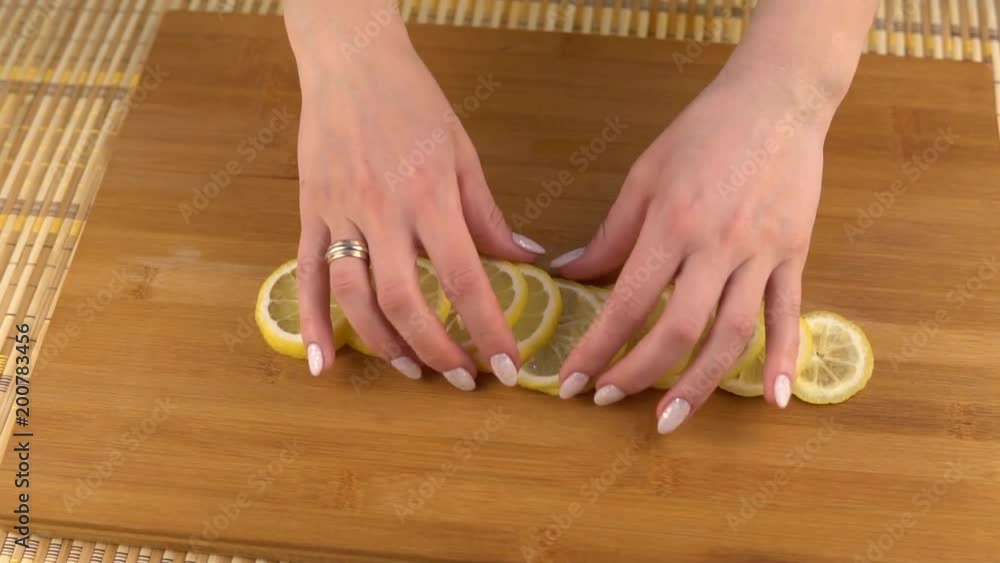 Laying slices of lemon on a plate. Cooking food on a wooden board