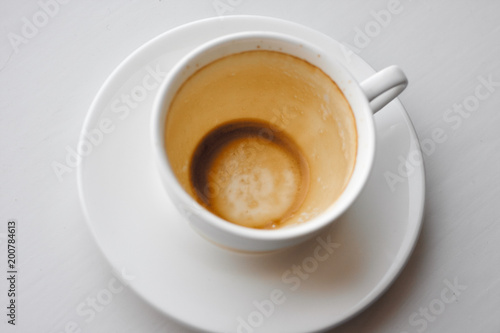 Empty used coffee cup on saucer covered with multiple stains on white background. Top view with copyspace for your text
