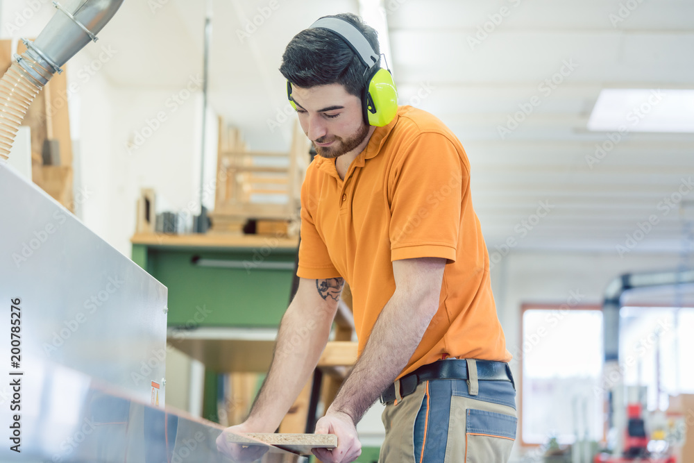 Carpenter working in furniture factory on computer controlled machine Carpenter working in furniture factory on computer controlled machine