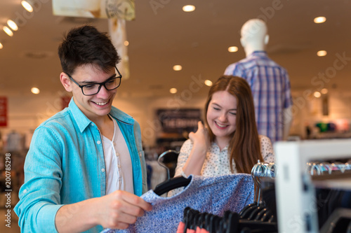 Man and woman in shopping choosing shirts