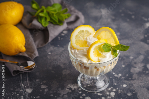 Lemon dessert. English lemon trifle, cheesecake, whipped cream, parfait. Fruit mousse in glass on a dark background. photo