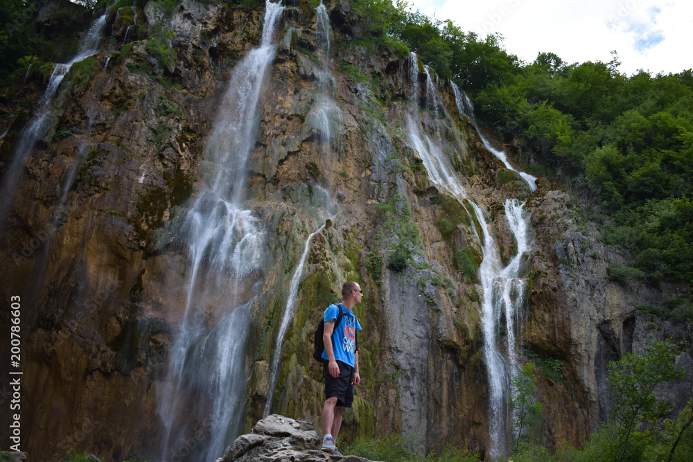 man standing on stone and enjoy view under great waterfall in Plitvice National Park Croatia 