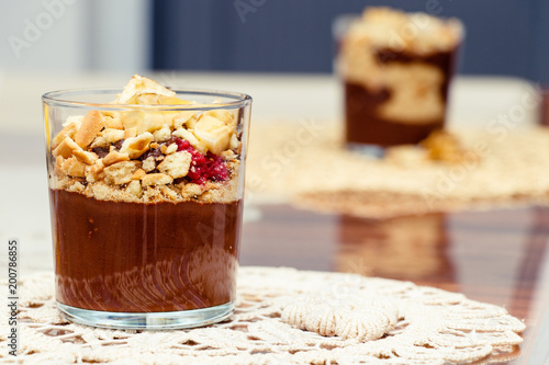 Delicious dessert with banana and biscuits chocolate pudding in glass cup on table