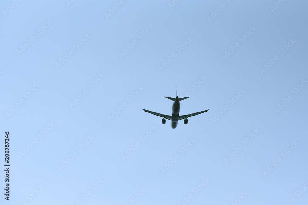 The passenger plane flies away into the blue sky. Back view The passenger plane flies away into the blue sky. Back view