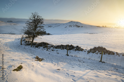 Beautiful snow covered Winter landscape at sunrise in Peak District in England
