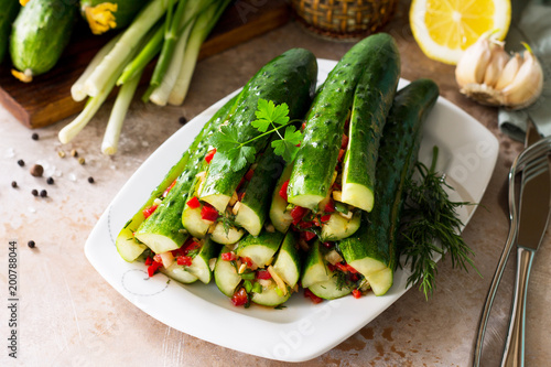 Korean traditional food Kimchi (Cucumber). Marinated cucumbers with vegetable filling (sweet pepper, garlic, onion, greens, tomato paste) on a stone or slate background.