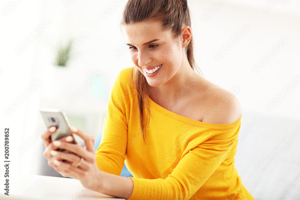 Happy woman relaxing at home with smartphone Happy woman relaxing at home with smartphone