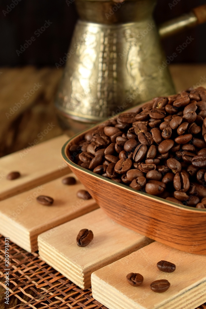Roasted coffee beans in a wooden bowl on boards