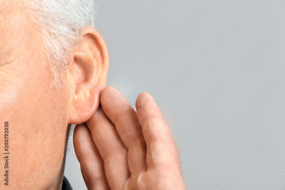 Obraz premium Mature man with hearing problem on grey background, closeup
