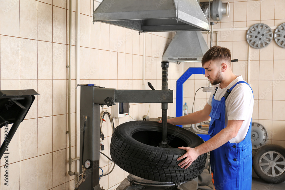 Mechanic changing car tire in service center Mechanic changing car tire in service center