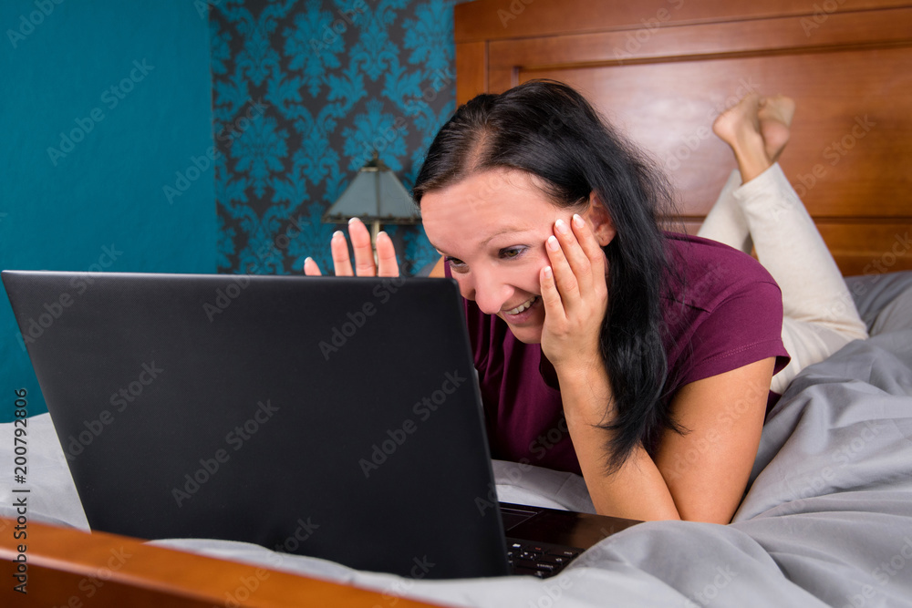 Woman lying on bed and looking at computer. Woman lying on bed and looking at computer.