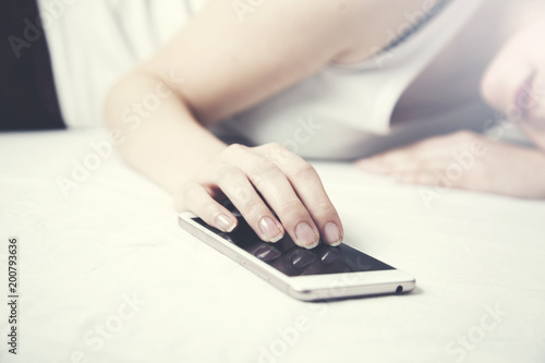 Woman sleeping in bed and holding a mobile phone