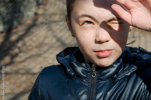 portrait of a girl looking at the sun and squinting eyes from the bright sun