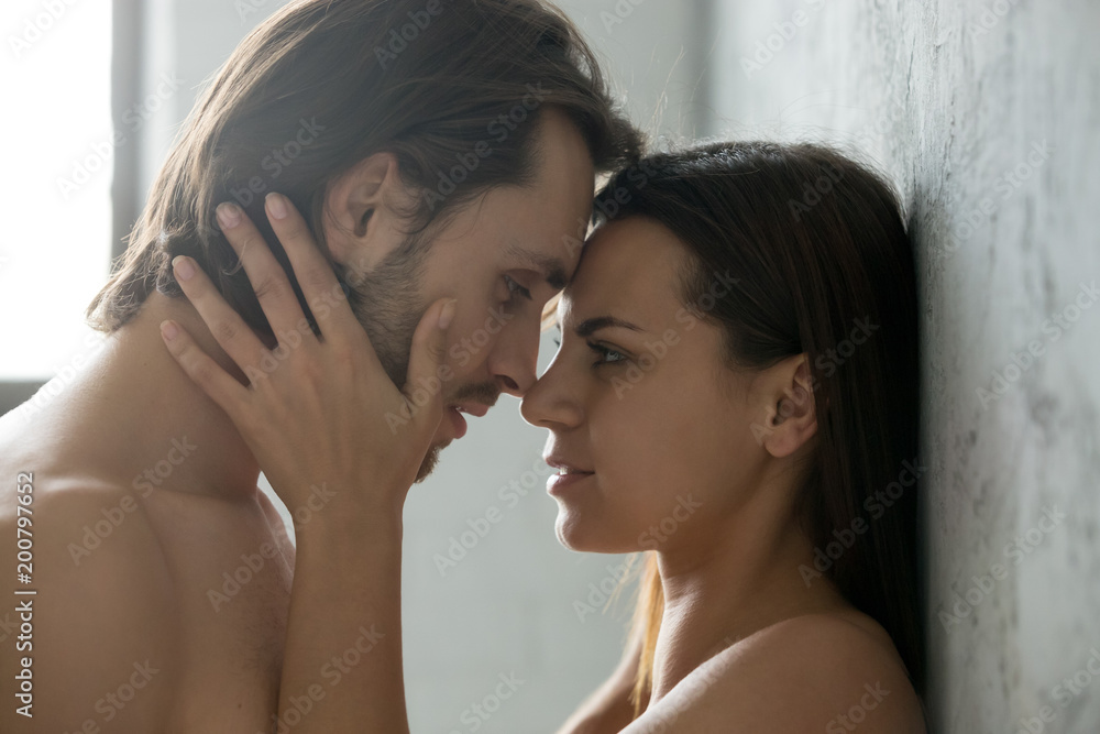 Romantic beautiful couple face to face, loving millennial affectionate woman touching man getting closer to kiss each other teasing enjoying sincere tenderness and intimacy, feeling desire, side view Romantic beautiful couple face to face, loving millennial affectionate woman touching man getting closer to kiss each other teasing enjoying sincere tenderness and intimacy, feeling desire, side view