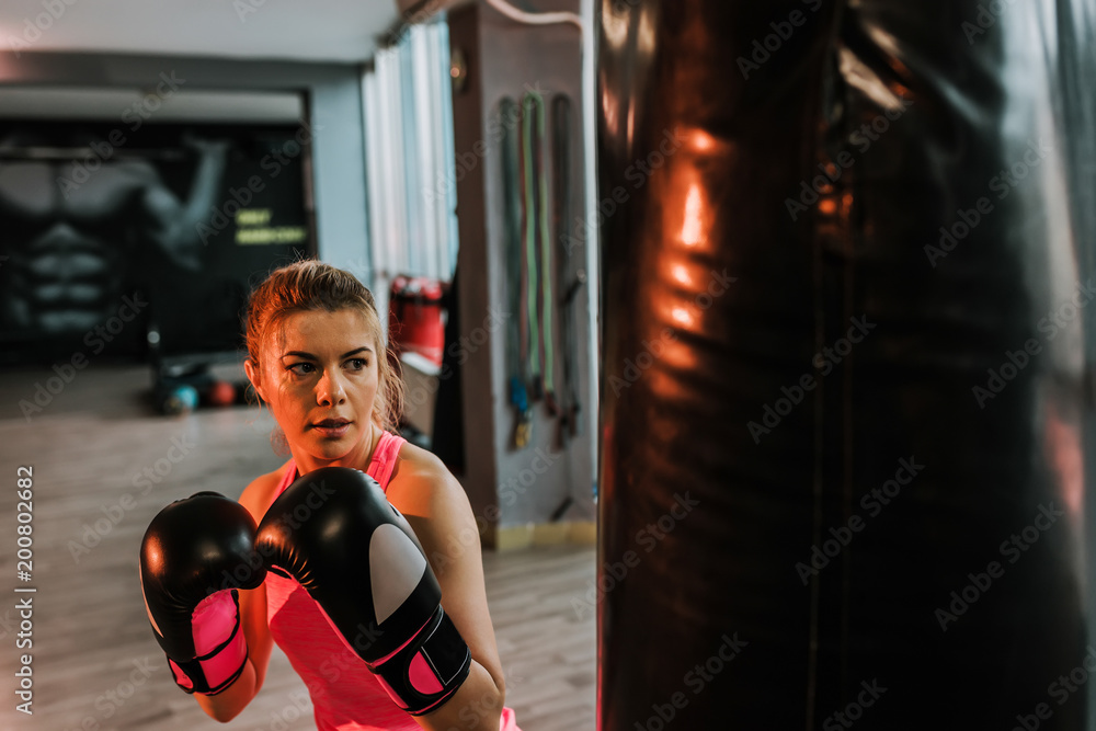 Portrait of blonde woman boxer who is training in gym.