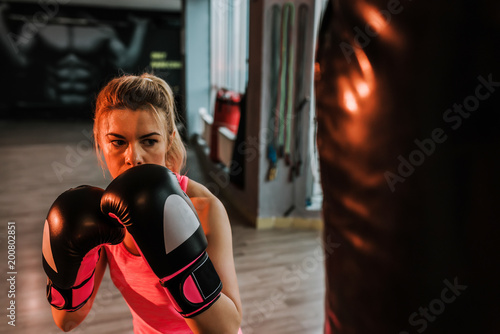 Close-up image of serious boxer girl practicing on a large bag.
