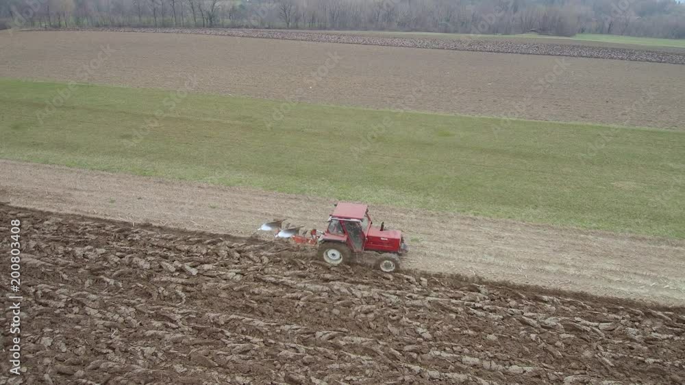 Agriculture and farming - Tractor plough a field in early spring aerial footage Agriculture and farming - Tractor plough a field in early spring aerial footage