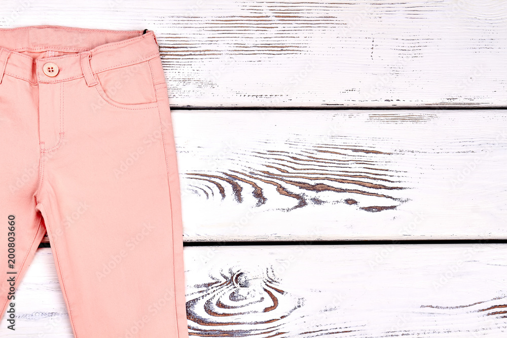 Teen girl peach color trousers. Girls colored summer skinny pants on wooden  bacground, copy space. Light cotton pants on white wooden background.  Photos | Adobe Stock