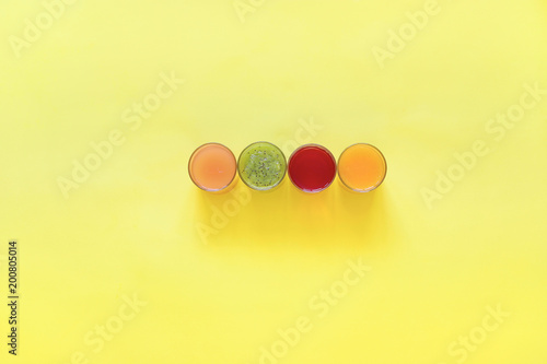 Fresh juices and fruit cut into slices on a yellow background