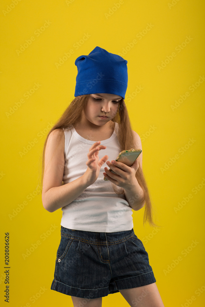 Beautiful caucasian girl posing on yellow isolated background in studio holding in hands mobile phone Beautiful caucasian girl posing on yellow isolated background in studio holding in hands mobile phone